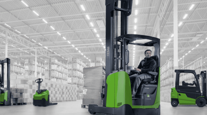 A worker operating an electric forklift inside a spacious warehouse, showcasing efficient material handling and storage.