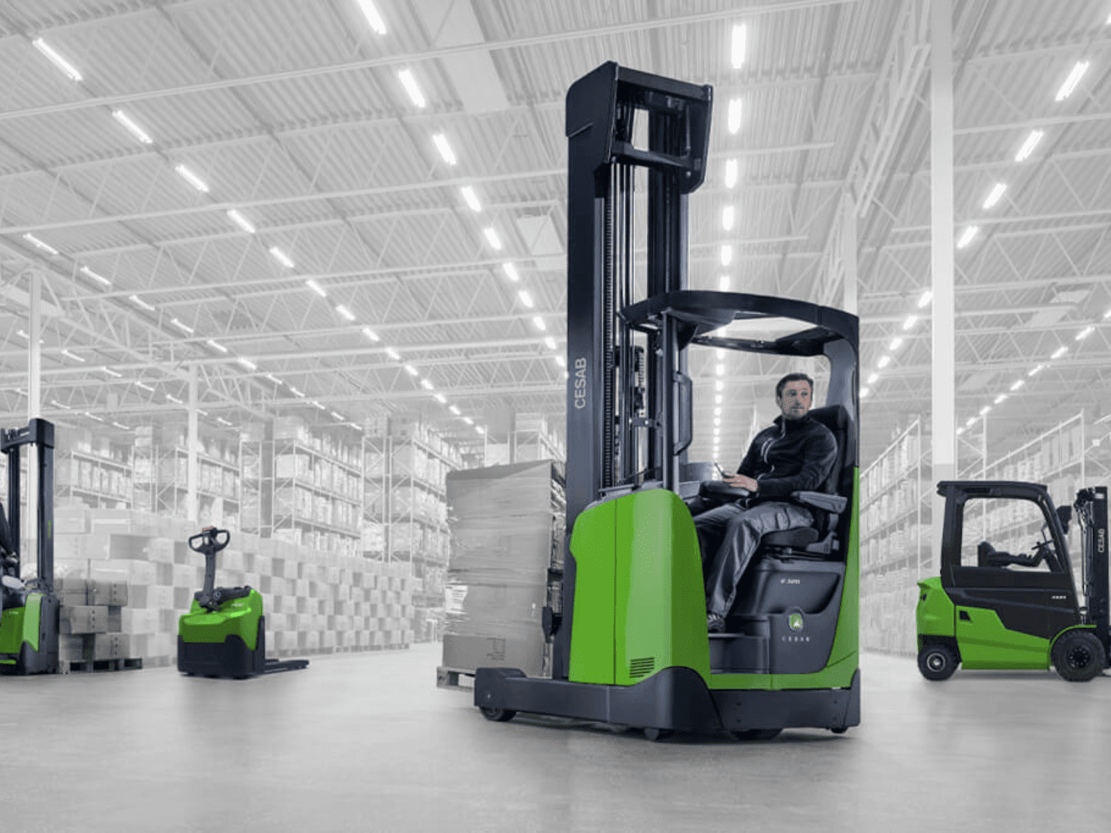 A worker operating an electric forklift inside a spacious warehouse, showcasing efficient material handling and storage.