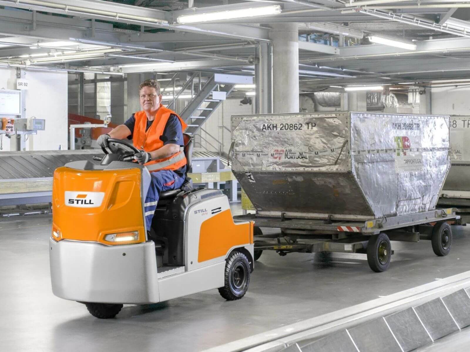 Airport Cargo Transport Vehicle in Action A worker driving a cargo transport vehicle in an airport, pulling a trailer loaded with luggage.