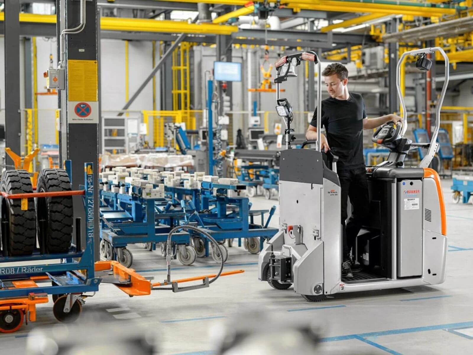 Modern Warehouse Automation with a Warehouse Vehicle A worker operating a modern warehouse vehicle in an industrial setting surrounded by equipment and pallets.