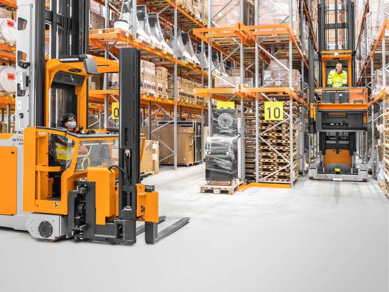 Modern Warehouse with Forklifts in Action Two forklifts operating in a well-organized warehouse environment with shelves stocked with boxes.