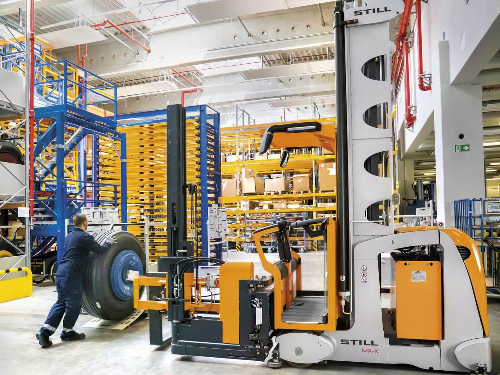 Automated Warehouse Forklift in Action A warehouse worker operates a STILL automated forklift to lift goods in a modern storage facility.