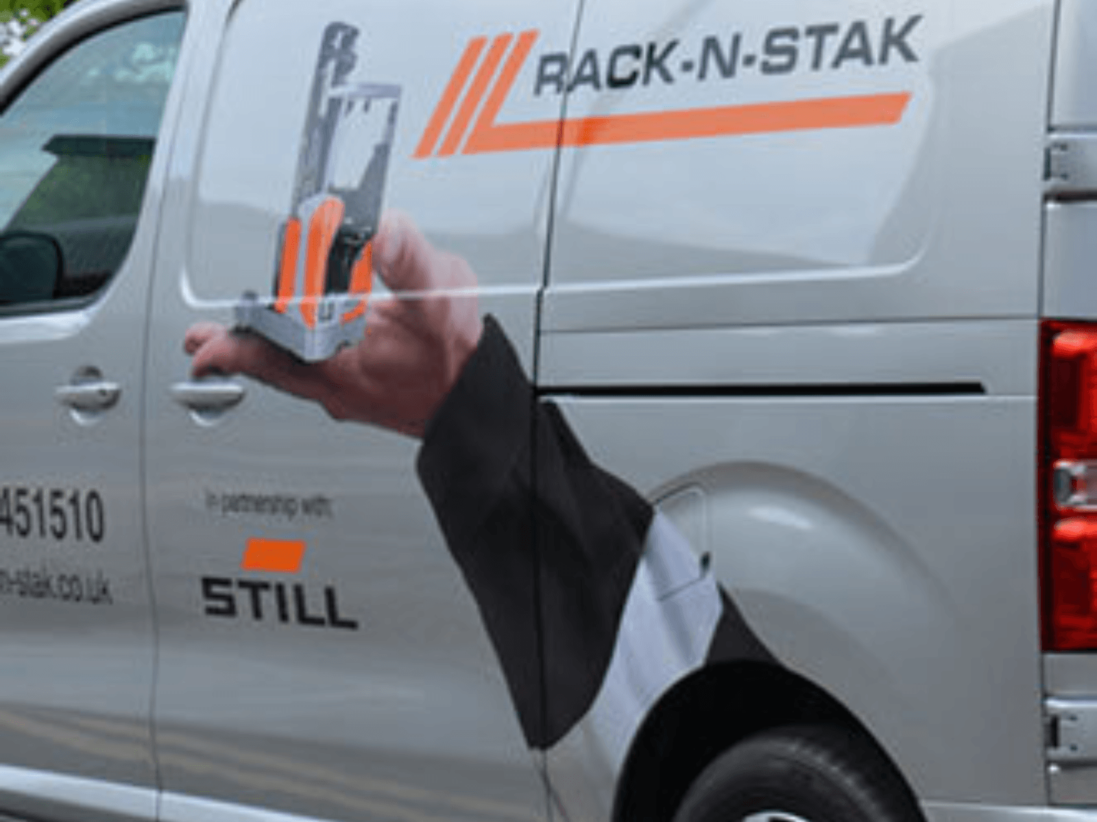 Delivery van featuring Rack-N-Stak branding and a hand holding a pallet rack, showcasing partnership with STILL.