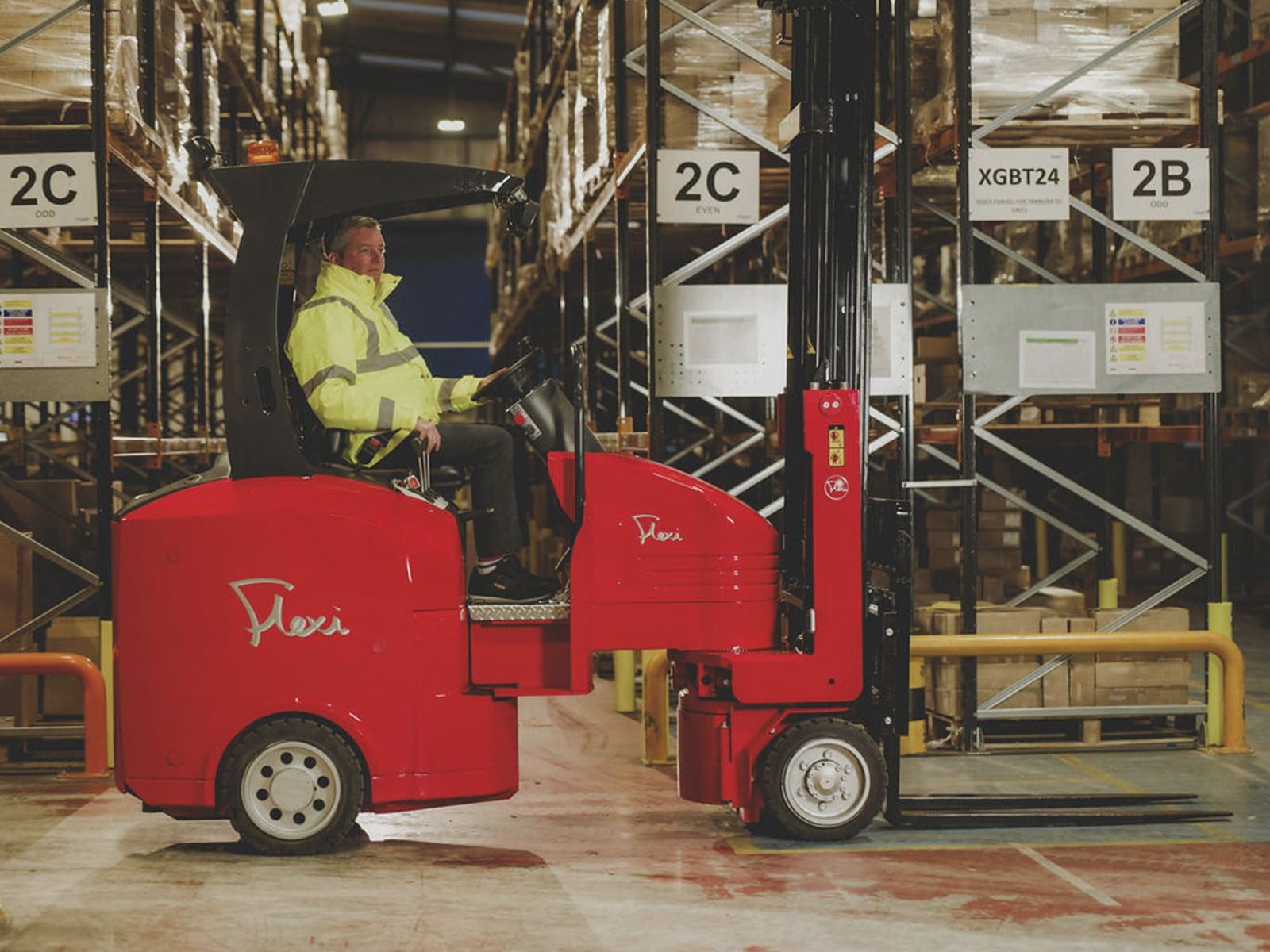 A worker operating a red forklift in a warehouse full of shelves and boxes, showcasing effective material handling.