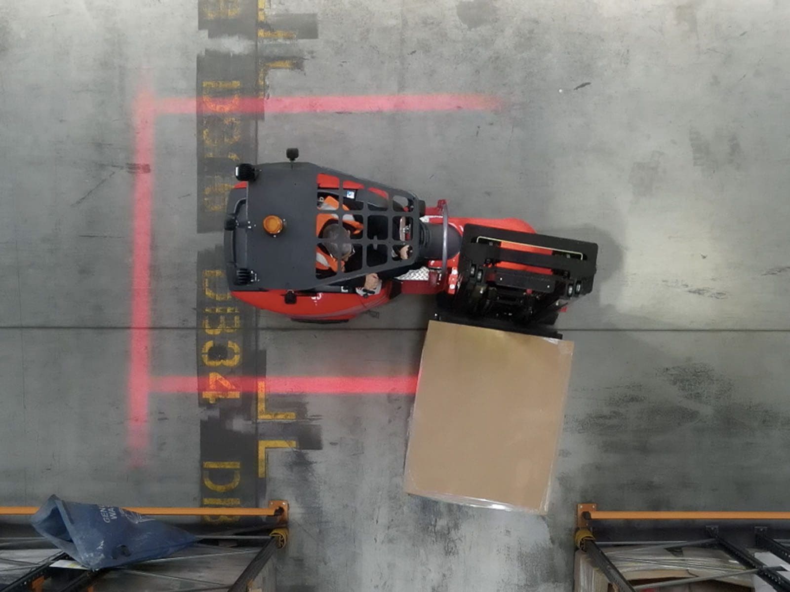 Overhead view of a forklift with a large cardboard box in a warehouse setting